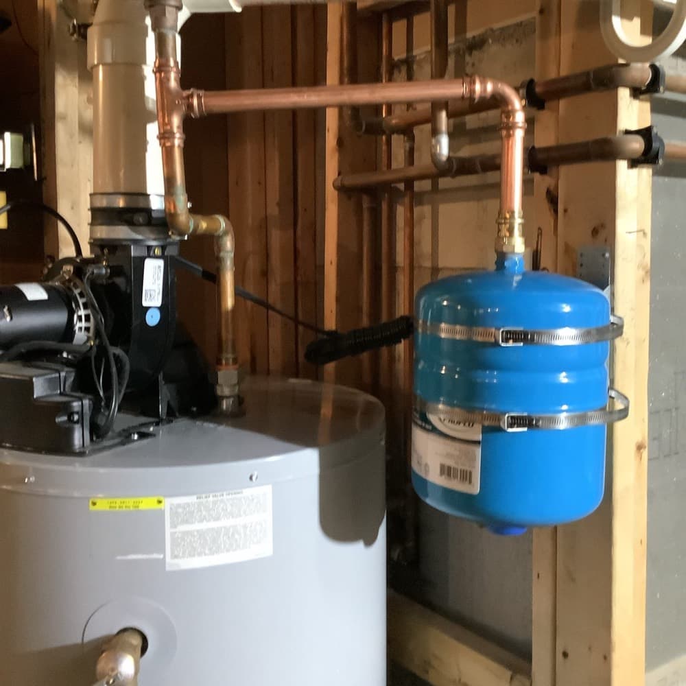 Water heater, copper piping, and blue expansion tank in a mechanical room